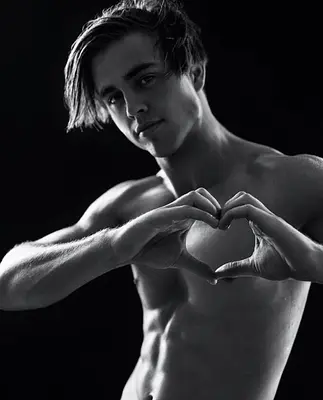 Sunshine Coast entertainer Tyler posing shirtless and making a heart shape with his hands during a dramatic black-and-white studio photoshoot.