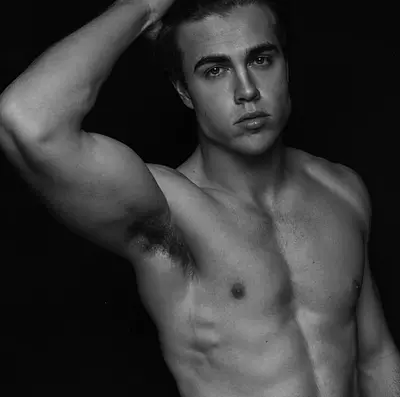 Sunshine Coast entertainer Tyler posing shirtless with one hand through his hair in a dramatic black-and-white studio portrait.