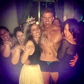 Hens Party Centre Of Attention Shirtless male entertainer posing with a group of laughing women during a lively hens party celebration.