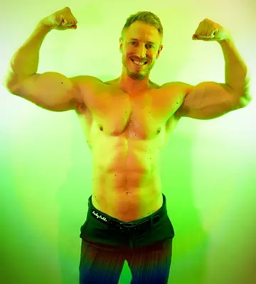 Sydney male entertainer Adam smiling and flexing both arms shirtless, ready for hens nights, birthday parties and private events.