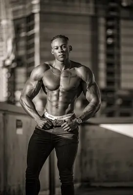 O’Niel posing shirtless with his hands on his hips in a black-and-white urban portrait, available to book as a Sunshine Coast life drawing model.