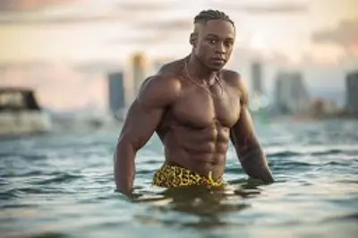 O’Niel standing shirtless in the water with a coastal skyline behind him, photographed for Sunshine Coast party and entertainment bookings.