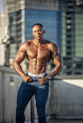 O’Niel posing shirtless in fitted jeans with his hands on his hips, available to hire as a cheeky Sunshine Coast apron waiter.