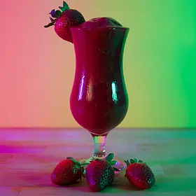 Frozen strawberry daiquiri garnished with fresh strawberries under pink and green neon lighting at a hens party cocktail making class.
