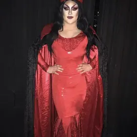 Perth drag queen Delvira posing in a glamorous red devil-inspired gown and cape, available to hire for Halloween parties and themed events.